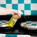 yellow kitchen degreaser GreenTab in forever bottle being used to clean a blue and white kitchen tile