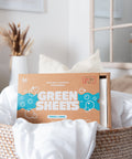 Green Company laundry strips fresh linen 64 pack sitting in a wicker laundry basket with white bed linen